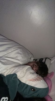 a person laying on top of a bed under a white comforter with a stuffed animal