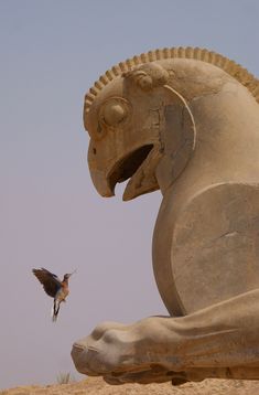 a bird is flying next to a large statue