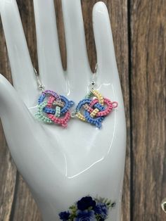 a pair of colorful beaded earrings sitting on top of a hand