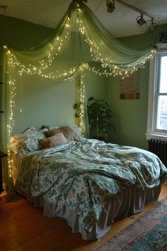 a bed with lights on the headboard and canopy over it in a room that has green walls