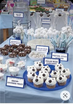 a table topped with lots of cupcakes covered in frosting and toppings