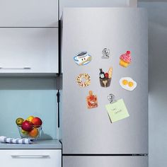 a refrigerator with magnets on the door and some fruit in a bowl next to it