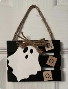 a halloween door hanger decorated with wooden blocks and a ghost face on it's side