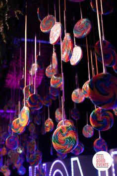 Colourful lollipops hanging above a grazing table with light up letters spelling 'WONKA' in the background Candy Factory Decorations, Charlie And The Chocolate Factory Themed Party, Wonka Chocolate Factory Themed Parties, Charlie And The Chocolate Factory Theme, Willy Wonka Background, Charlie Chocolate Factory Party, Charlie And The Chocolate Factory Decorations, Charlie And The Chocolate Factory Party Decorations, Willy Wonka Classroom Theme