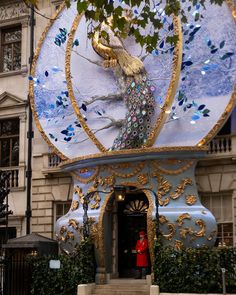 a blue and gold clock with a peacock on it's face in front of a building