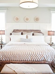 a bed with white sheets and pillows in a bedroom next to two lamps on either side of the bed