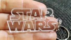 a hand holding a plastic keychain with the word star wars printed on it