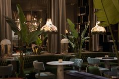 the interior of a restaurant with green velvet booths and brass lamps on either side of the tables