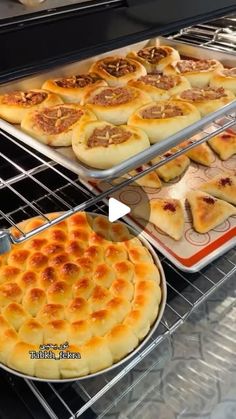 two trays filled with different types of pizza on top of metal racks in a bakery