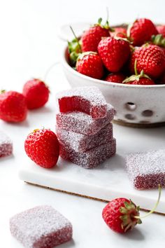 some strawberries are sitting in the bowl next to small pieces of cake