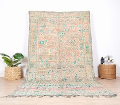 an old rug is sitting on the floor next to a potted plant and wicker basket