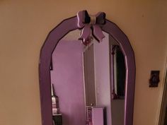 a purple mirror with a bow on the top of it and some drawers in front of it