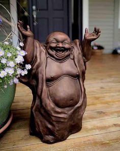 a statue of a laughing buddha sitting next to a potted planter with flowers in it