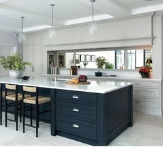 a large kitchen with an island in the middle and four stools at the end