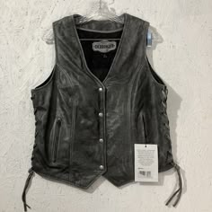 Introducing a brand new, never worn ladies motorcycle vest from the Derringer Genuine Leather collection. Made of high-quality distressed grey leather, this vest features a zipper accent, snap closures, and inner pockets for added convenience. The vest is a size Large and has a jacket/coat length that can be seen in the provided pictures. Perfect for any biker or motorcycle enthusiast, this vest is a must-have for your collection. It's a versatile piece that can be worn in the summer, fall, or spring. While it does require dry cleaning only, the quality of the leather and the attention to detail in the design make it well worth the investment. Order now and add this stylish, yet functional vest to your wardrobe! Picture shows the measurements and the condition. If questions ask prior to bi Sleeveless Leather Jacket Outfit, Sleeveless Leather Jacket, Ladies Motorcycle, Biker Outfit, Motorcycle Vest, Biker Vest, Leather Jacket Outfits, Leather Cuts, Fire Fits