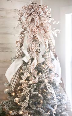 a christmas tree decorated with white and brown bows