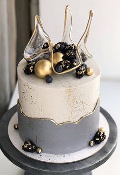 a white and grey cake with gold decorations on it's top, sitting on a table