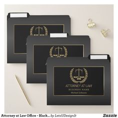 three black folders with gold accents and a logo on them are shown next to a pen