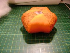 an orange stuffed animal sitting on top of a cutting board next to a sewing machine