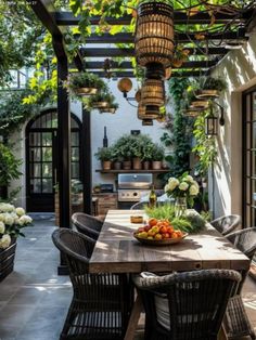 an outdoor dining area with potted plants and flowers on the table, surrounded by wicker chairs