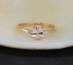 "This Engagement ring features a Peach sapphire in oval cut. The sapphire is natural untreated, eye clean and sparkling. It is set in a 3-stone setting flanked by 2 diamonds. This ring would make a perfect engagement ring, anniversary ring or promise ring. The setting is 14k Rose gold, diamonds SI/H. Details: Center stone: Sapphire approx. 0.75ct (5x7mm)  natural, unheated, SI clarity Accented stone: Diamonds: SI/H, TDW 0.1ct This ring is ready to ship. We offer FREE SHIPPING Worldwide If you ne Oval Engagement Ring 3 Stone, Engagement Ring 3 Stone, Engagement Ring Gemstone, Ring 3 Stone, Peach Sapphire Engagement Ring, 3 Stone Ring, Peach Sapphire, Oval Engagement Ring, 3 Stone Rings