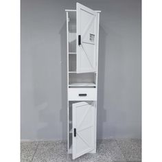 a tall white cabinet with an open door on the top and bottom shelf, in front of a gray wall