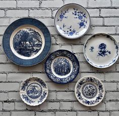 blue and white plates are arranged on a brick wall