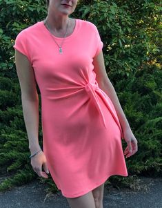 a woman in a pink dress posing for the camera with her hand on her hip