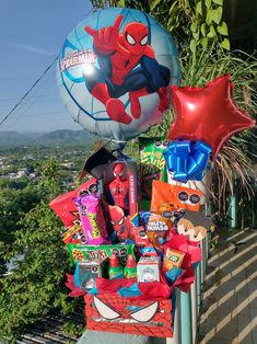 some balloons and other items are sitting on a rail near a tree with mountains in the background