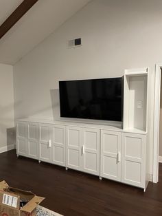 a large flat screen tv mounted to the side of a white entertainment center in a living room