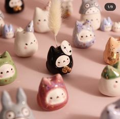 small ceramic animal figurines are arranged on a pink surface with a feather sticking out of one