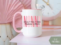 a pink and white coffee mug sitting on top of a table next to a clock