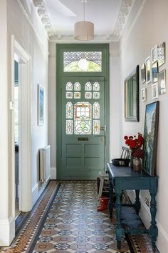 an entryway with a green door and tiled floor, framed pictures on the wall