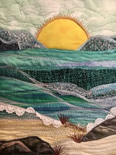 a quilted wall hanging with the sun and ocean waves on it's side