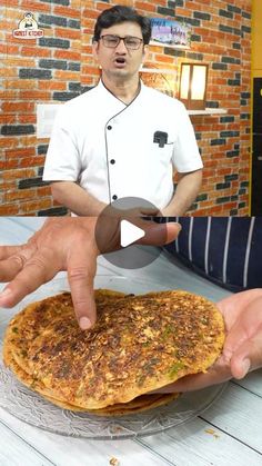 a man is making food on top of a plate with his fingers in the air