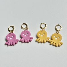 three different colored octopus shaped key chains on a white surface, one is yellow and the other is pink