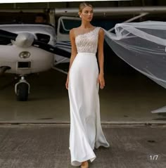 a woman standing in front of an airplane wearing a wedding dress with sheer veils