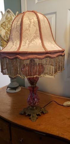 a lamp sitting on top of a wooden table next to a dresser with drawers in the background