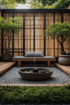 an outdoor garden with trees, rocks and gravel in the center is surrounded by bamboo screens