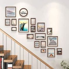 there are many pictures on the wall next to the stair case and bookshelf