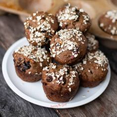 a white plate topped with chocolate muffins covered in sprinkles on top of a wooden table