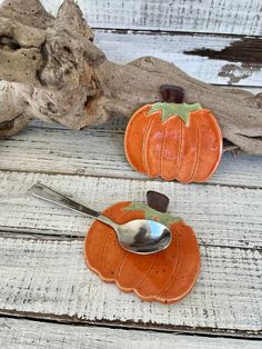 two small pumpkins are sitting next to a spoon