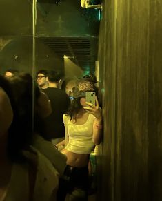 a woman taking a selfie in a mirror while standing next to a group of people