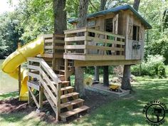 there is a tree house with a slide in the yard