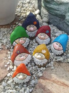 several gnomes are sitting on the rocks in front of a potted planter