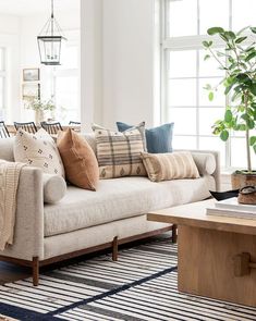 a living room filled with lots of furniture and pillows on top of a rug next to a coffee table