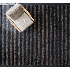 a black and white striped rug with a wooden chair next to it on the floor