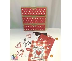 some cards are sitting on a table next to a card box and envelope with hearts