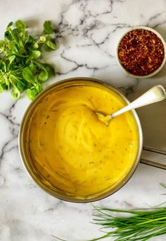 two bowls of mustard and herbs on a marble table