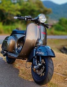 a scooter parked on the side of a road near some grass and trees